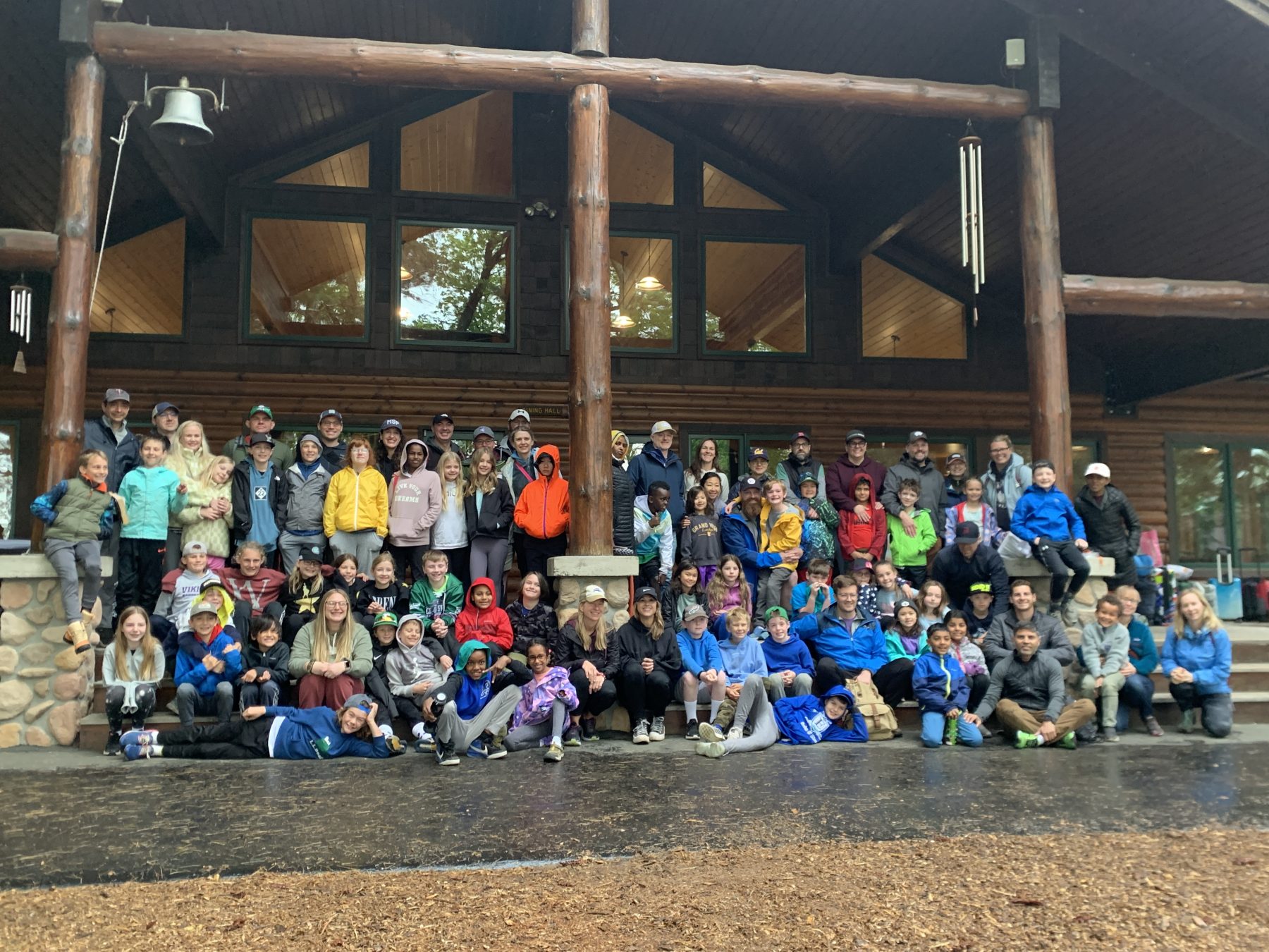 A school group sits in a large group on stairs smiling at the camera at Camp Foley 