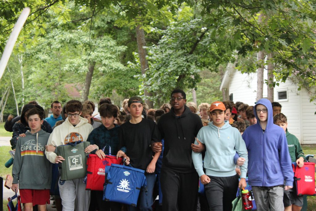 boy campers with arms linked marching in a line 