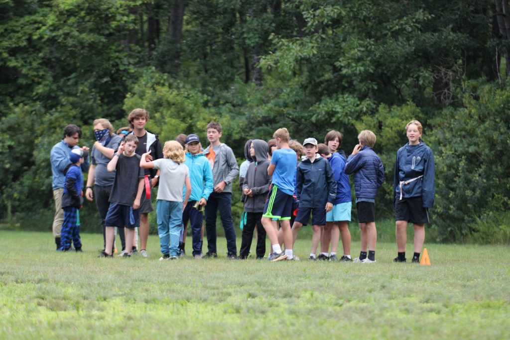 Group of boys waiting on the soccer field with 2 counselors 