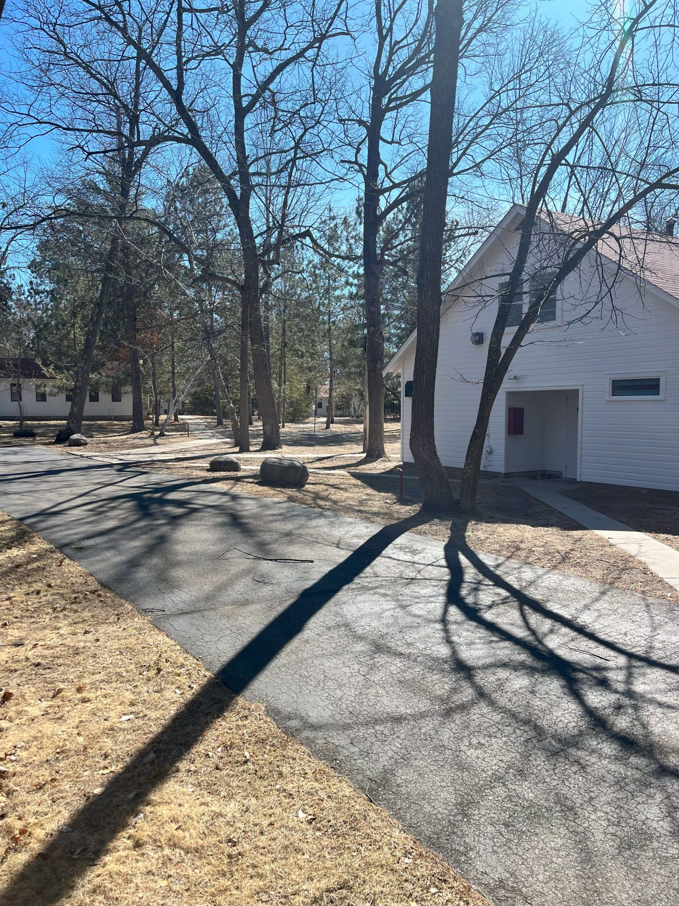 A landscape look at camp Foley with 2 white buildings in the distance, and trees casting long shadows