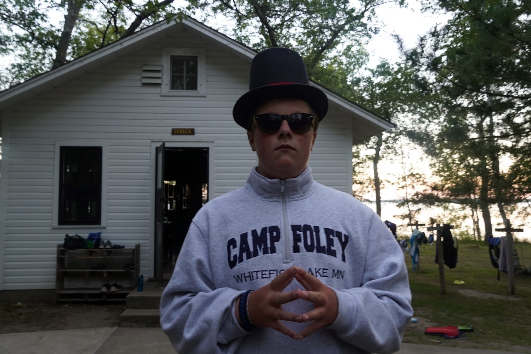 Young man wears a top hat and sunglasses to protect his eyes 