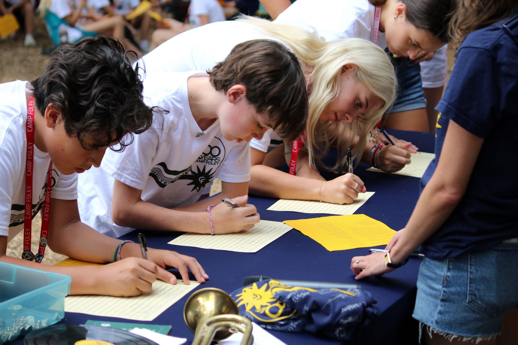 Children bend over a tale to sign a piece of paper 