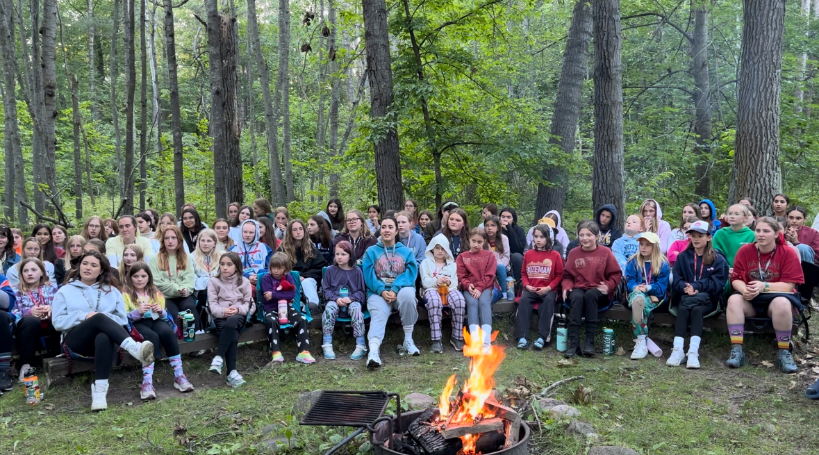 a group of campers watch campfire performance 