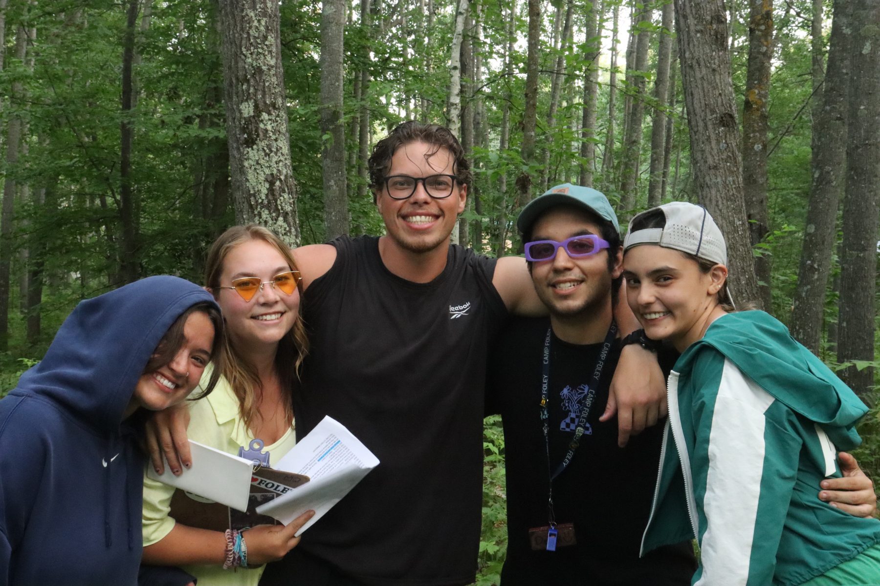 a group of counselors pose in front of trees 