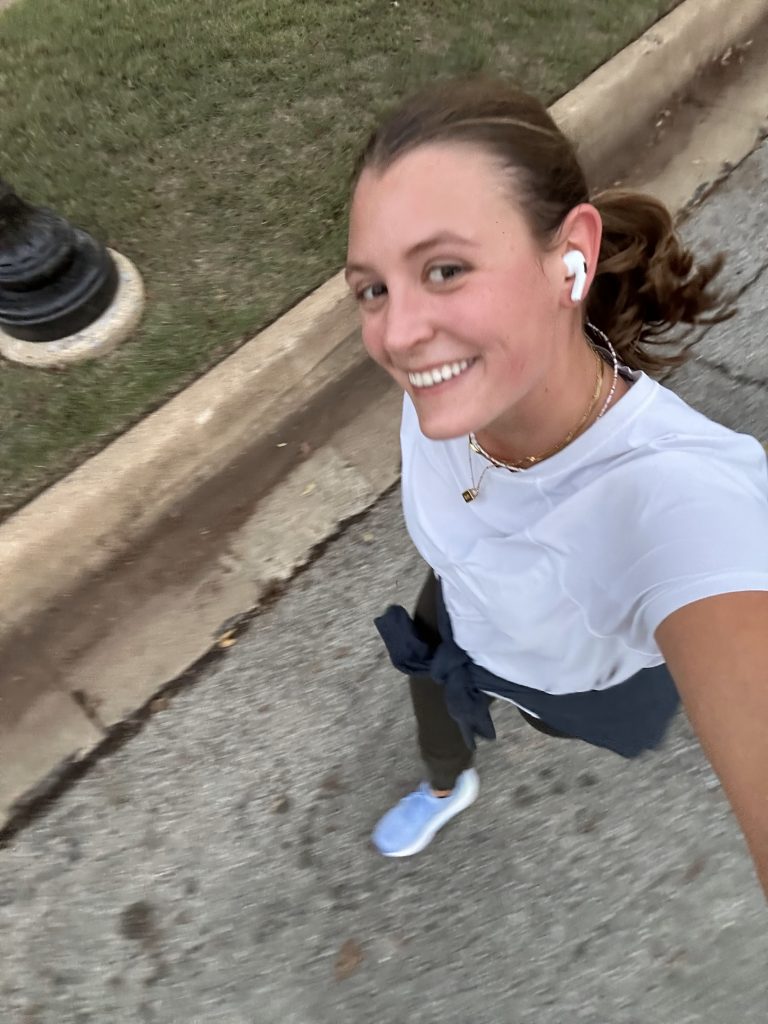 A girl takes a selfie while walking in a white shirt 