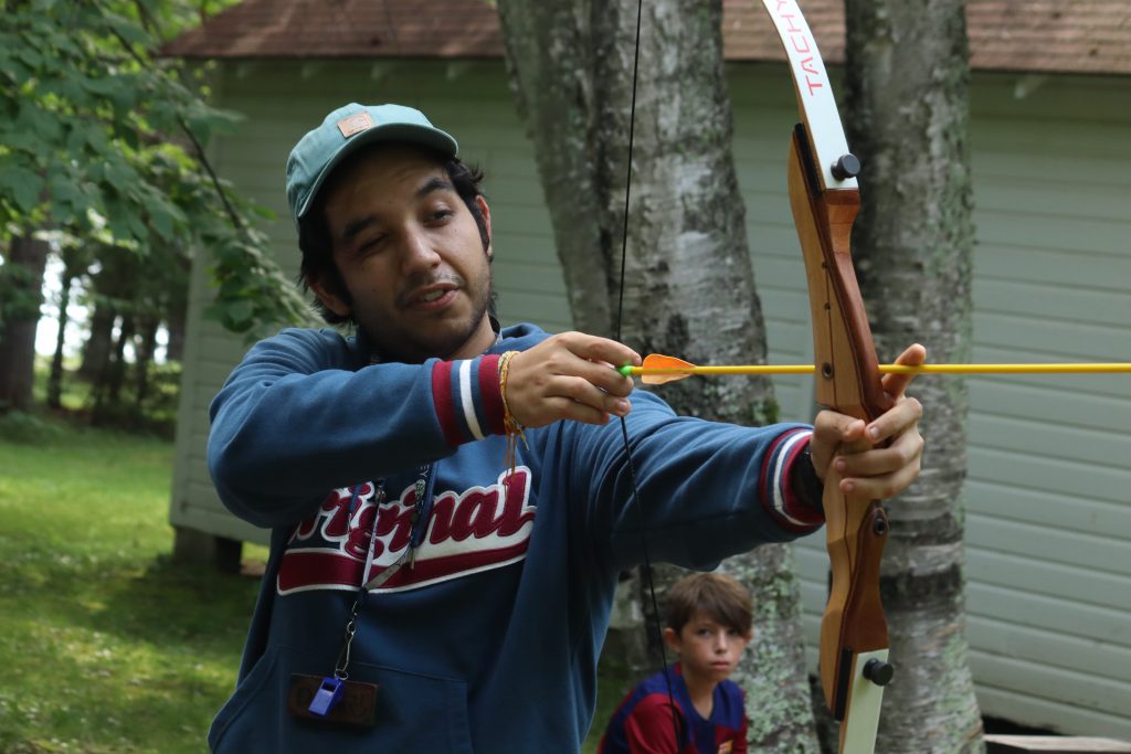 A male Foley counselor aims a bow and arrow 