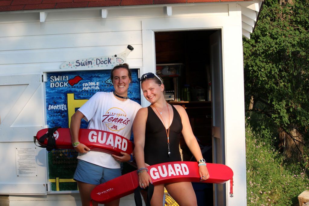 2 camp Foley counselors pose in front of the buddy board 